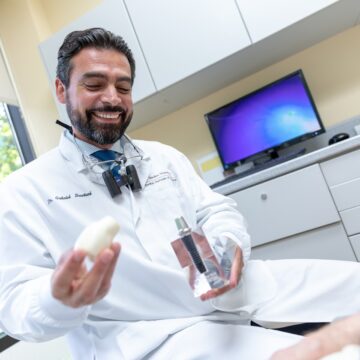 Dr. Gabriel Boustani smiling and holding the teeth model in their hand